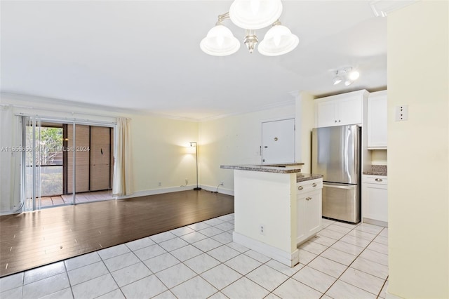 kitchen featuring a kitchen island, stainless steel refrigerator, light wood-type flooring, and white cabinets