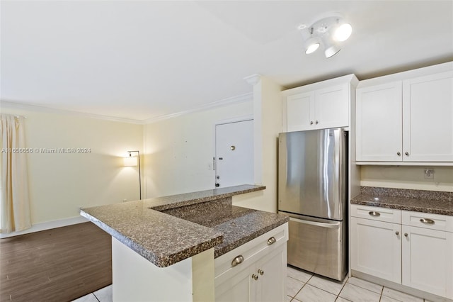 kitchen with light wood-type flooring, white cabinetry, dark stone counters, and stainless steel refrigerator