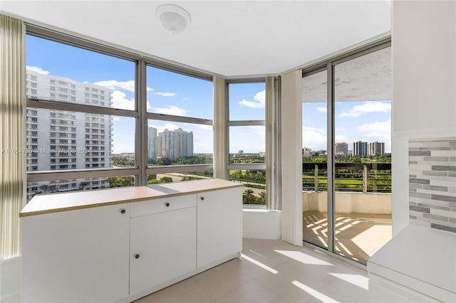 interior space featuring backsplash, light tile patterned floors, and white cabinetry