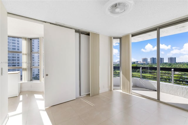 unfurnished room with expansive windows, visible vents, tile patterned floors, and a city view