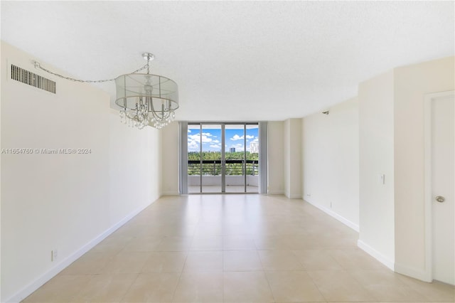 empty room featuring a wall of windows, a chandelier, and a textured ceiling