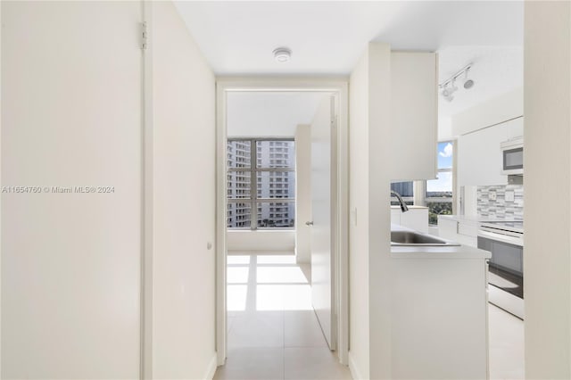 hall featuring sink and light tile patterned floors