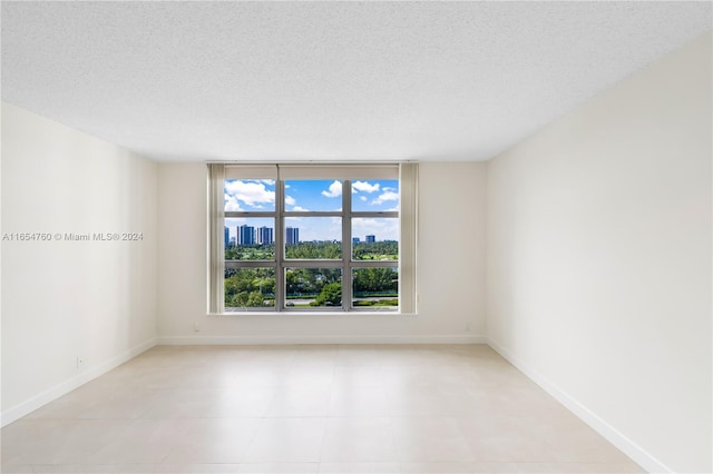 empty room featuring a city view, a textured ceiling, and baseboards