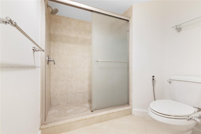 bathroom with tile patterned floors, toilet, and a stall shower