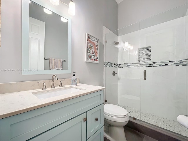 bathroom with a shower with door, vanity, and toilet