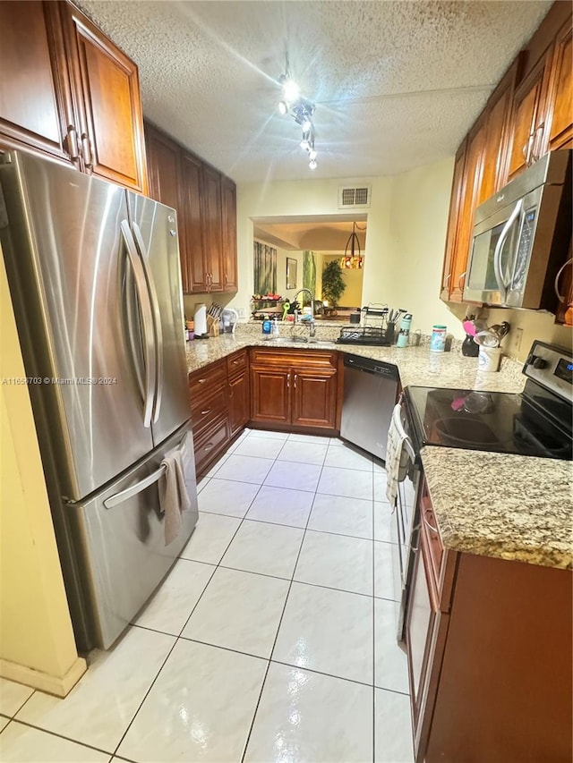 kitchen with light stone counters, kitchen peninsula, stainless steel appliances, and light tile patterned flooring