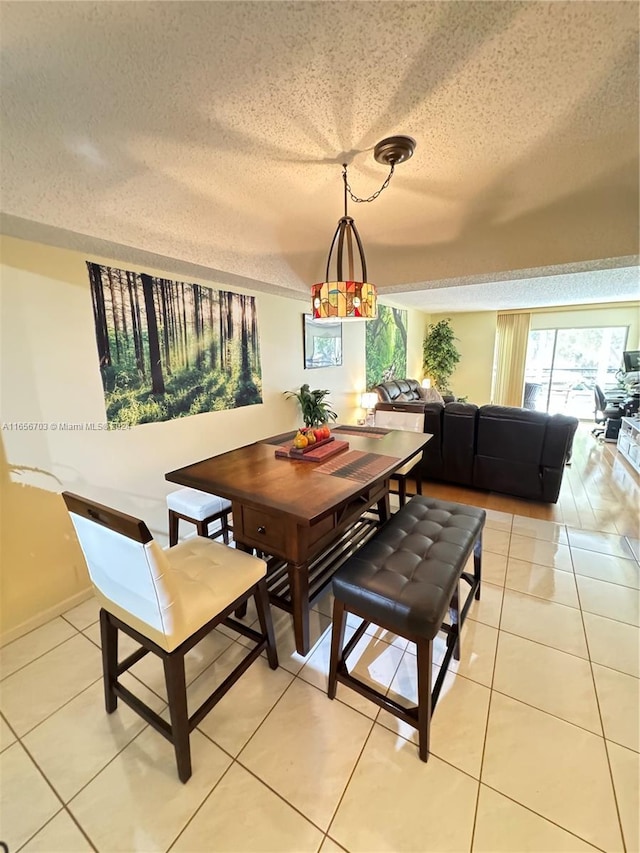 dining area featuring light tile patterned floors and a textured ceiling