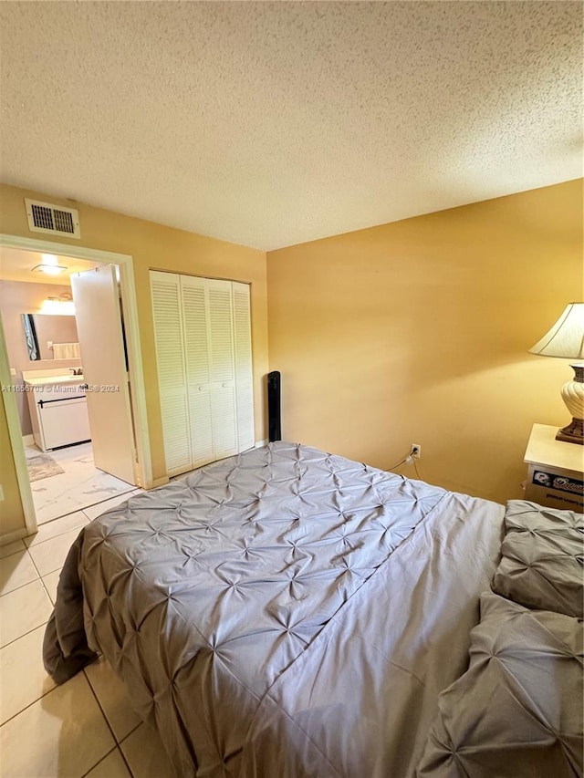 bedroom featuring a textured ceiling, light tile patterned floors, and a closet