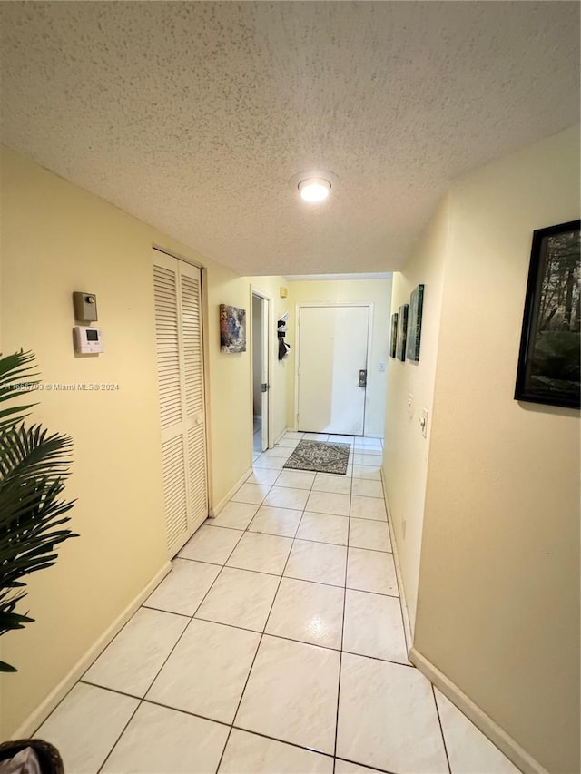 hallway with light tile patterned floors and a textured ceiling