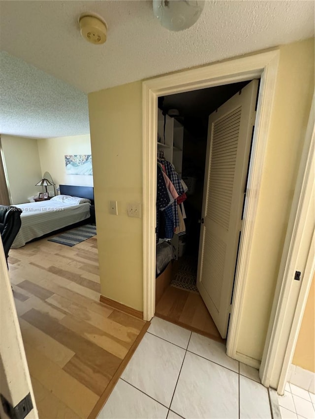 corridor with a textured ceiling and light hardwood / wood-style floors