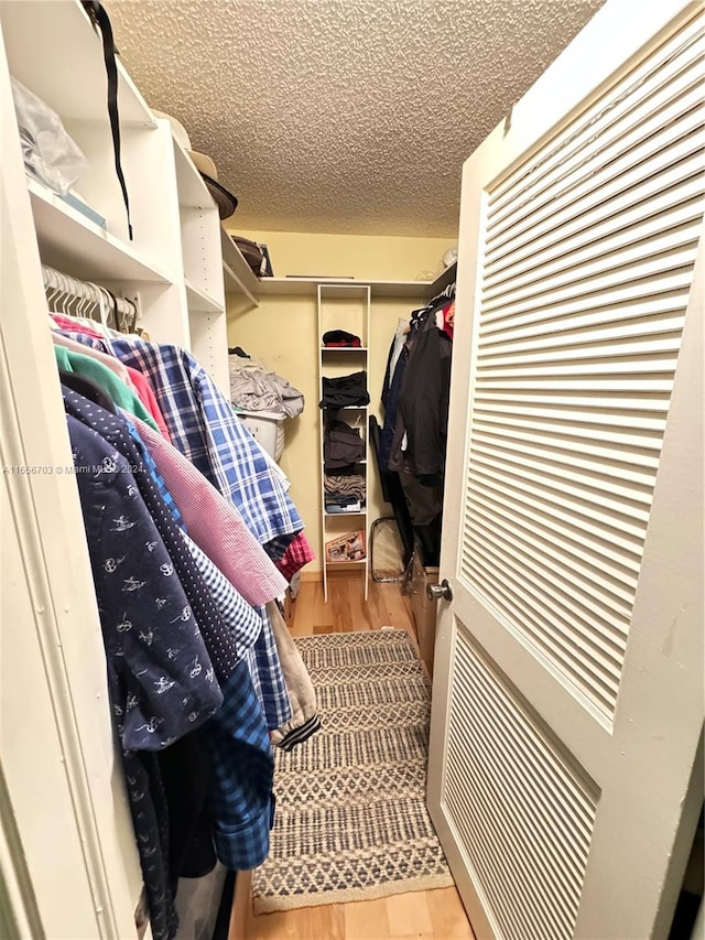 walk in closet with light hardwood / wood-style flooring