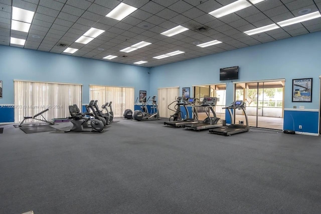 workout area featuring a paneled ceiling and a high ceiling