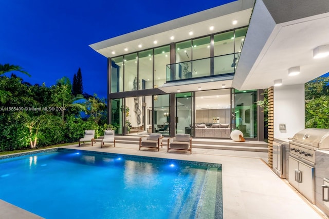 pool at twilight with a patio, an outdoor hangout area, an outdoor kitchen, and area for grilling