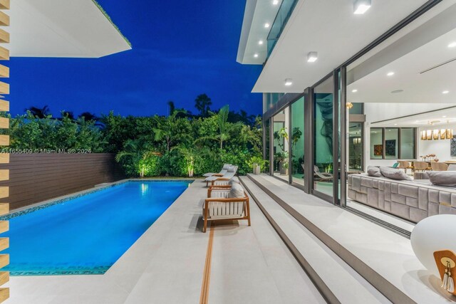 pool at night featuring a patio area