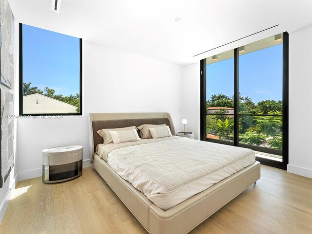 bedroom with a wall of windows, light wood-type flooring, and multiple windows