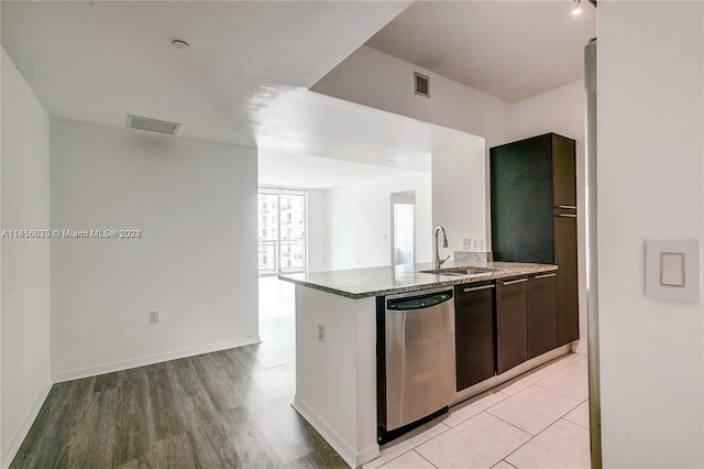 kitchen featuring dark brown cabinets, stone countertops, light hardwood / wood-style floors, stainless steel dishwasher, and sink