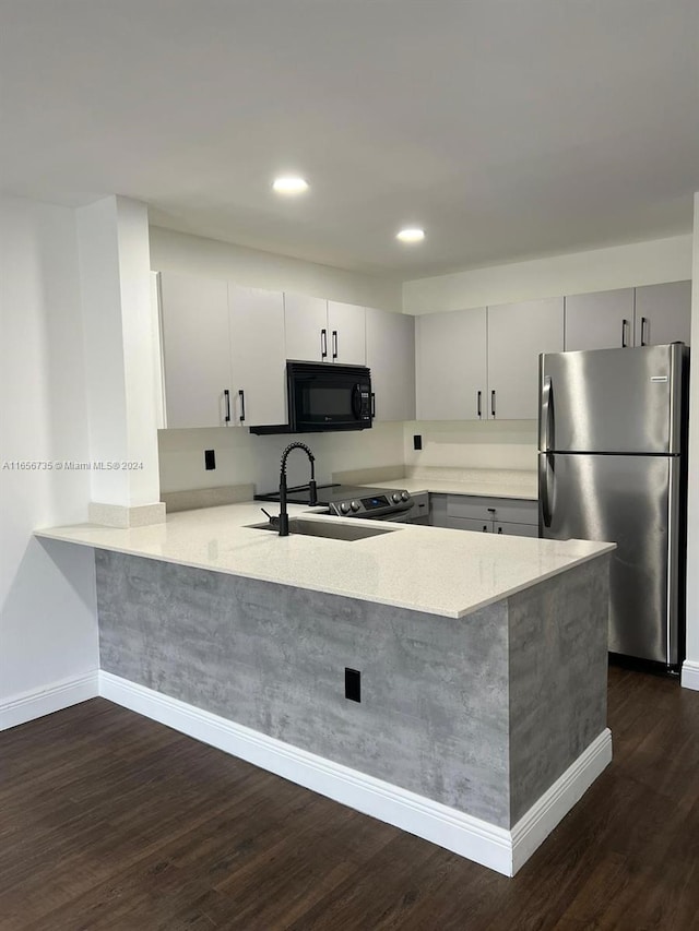 kitchen with dark wood-type flooring, kitchen peninsula, stainless steel refrigerator, and sink