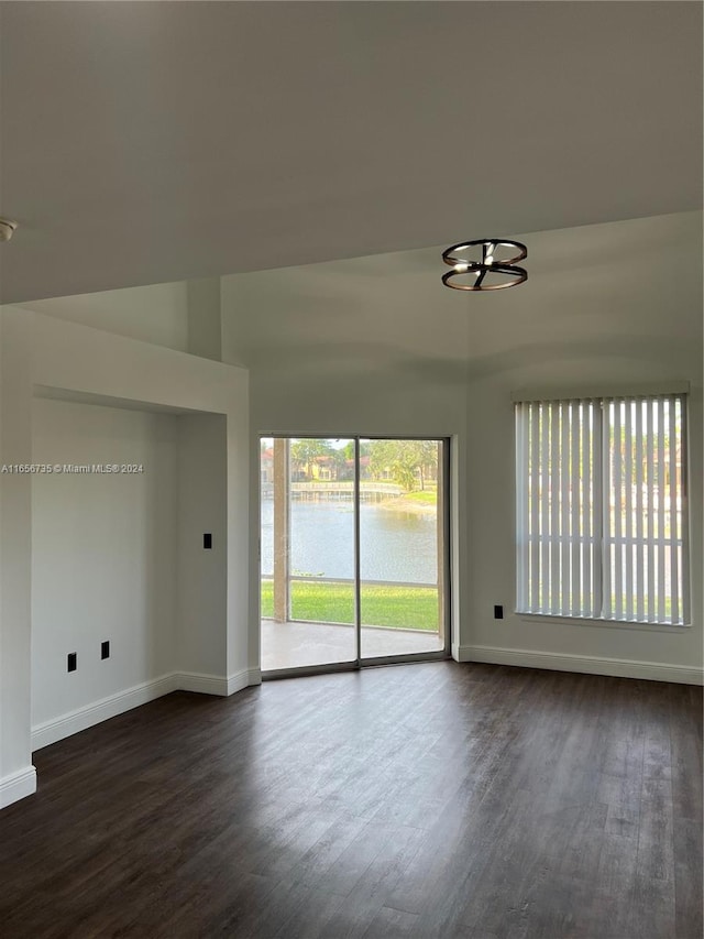 unfurnished room with dark wood-type flooring and a water view