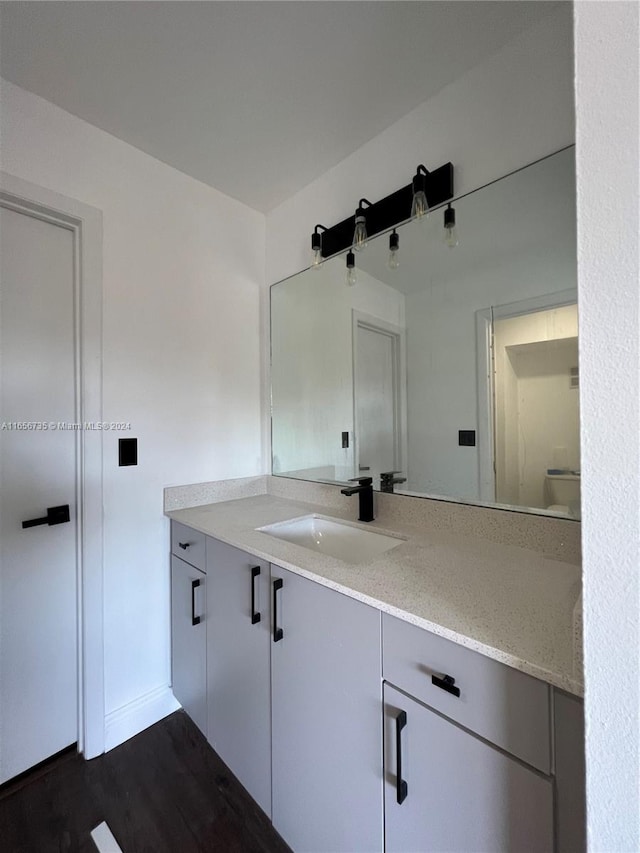 bathroom with vanity, toilet, and hardwood / wood-style flooring