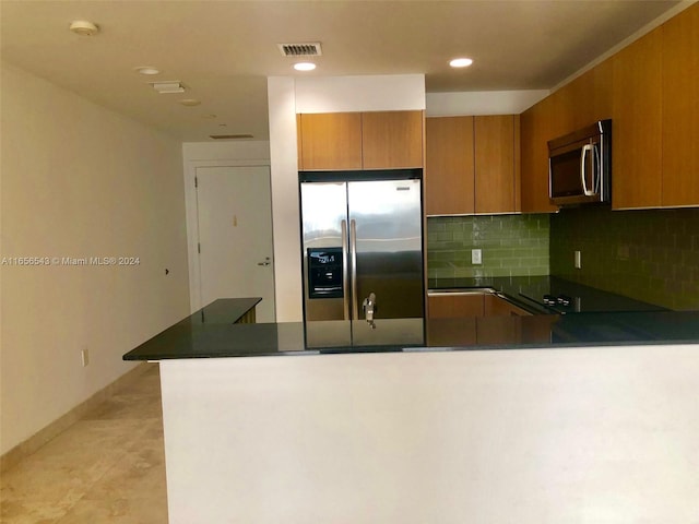 kitchen featuring kitchen peninsula, appliances with stainless steel finishes, and tasteful backsplash