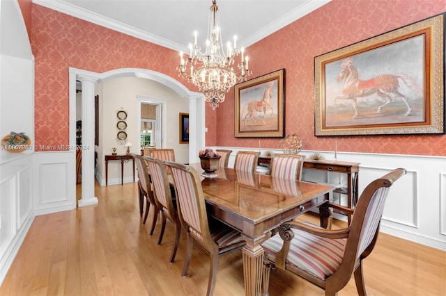 dining area featuring light wood-type flooring, crown molding, and decorative columns