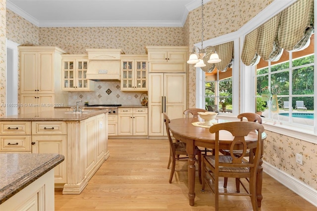 kitchen featuring light hardwood / wood-style flooring, an inviting chandelier, decorative light fixtures, ornamental molding, and cream cabinets