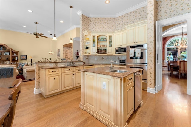 kitchen featuring kitchen peninsula, decorative light fixtures, a kitchen island with sink, and crown molding