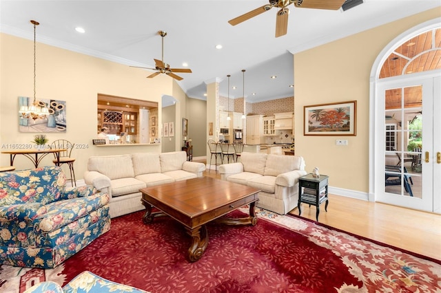 living room with ornamental molding, ceiling fan with notable chandelier, and hardwood / wood-style flooring