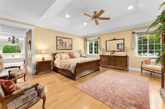 bedroom with light hardwood / wood-style flooring, multiple windows, ceiling fan with notable chandelier, and crown molding