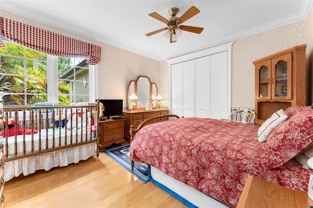 bedroom with ornamental molding, hardwood / wood-style floors, ceiling fan, and a closet