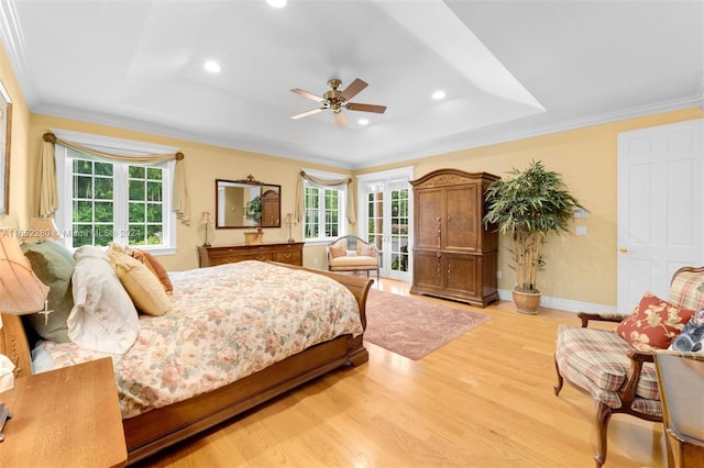 bedroom featuring light wood-type flooring, crown molding, a tray ceiling, and ceiling fan