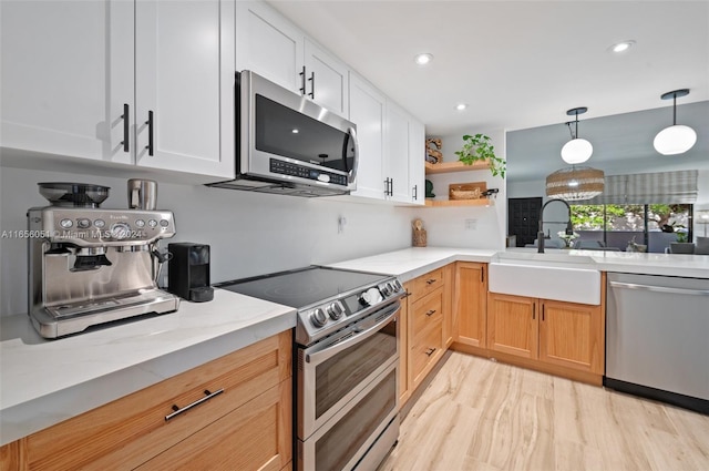 kitchen with decorative light fixtures, appliances with stainless steel finishes, light hardwood / wood-style floors, and white cabinetry