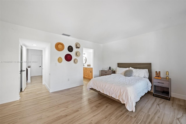 bedroom featuring light hardwood / wood-style flooring and connected bathroom