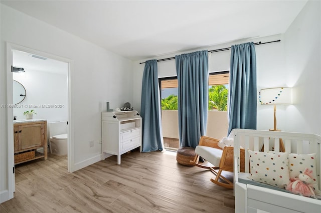 bedroom featuring light hardwood / wood-style floors, a nursery area, and ensuite bathroom