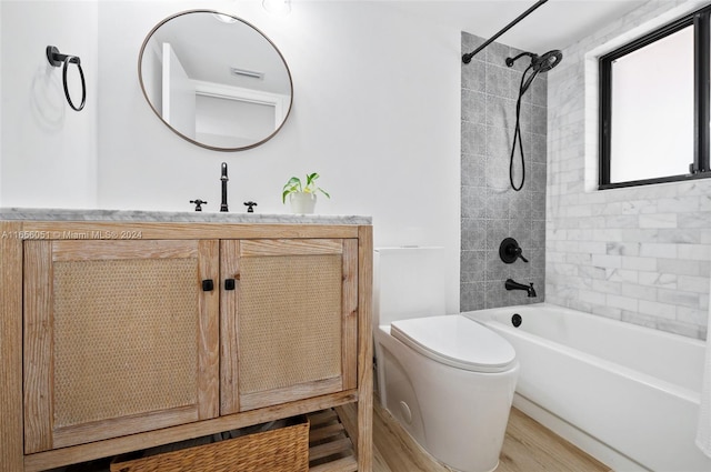 full bathroom featuring hardwood / wood-style flooring, vanity, toilet, and tiled shower / bath