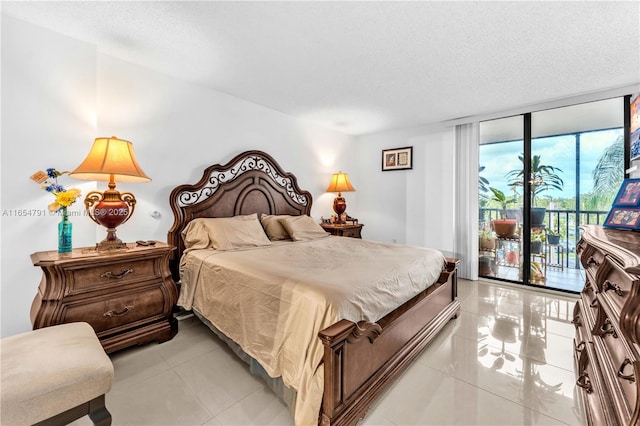 tiled bedroom featuring access to outside, a textured ceiling, and a wall of windows