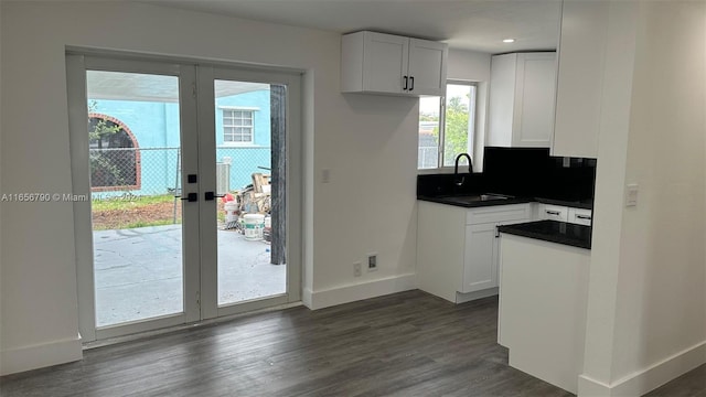 kitchen featuring sink, tasteful backsplash, french doors, dark wood-type flooring, and white cabinetry