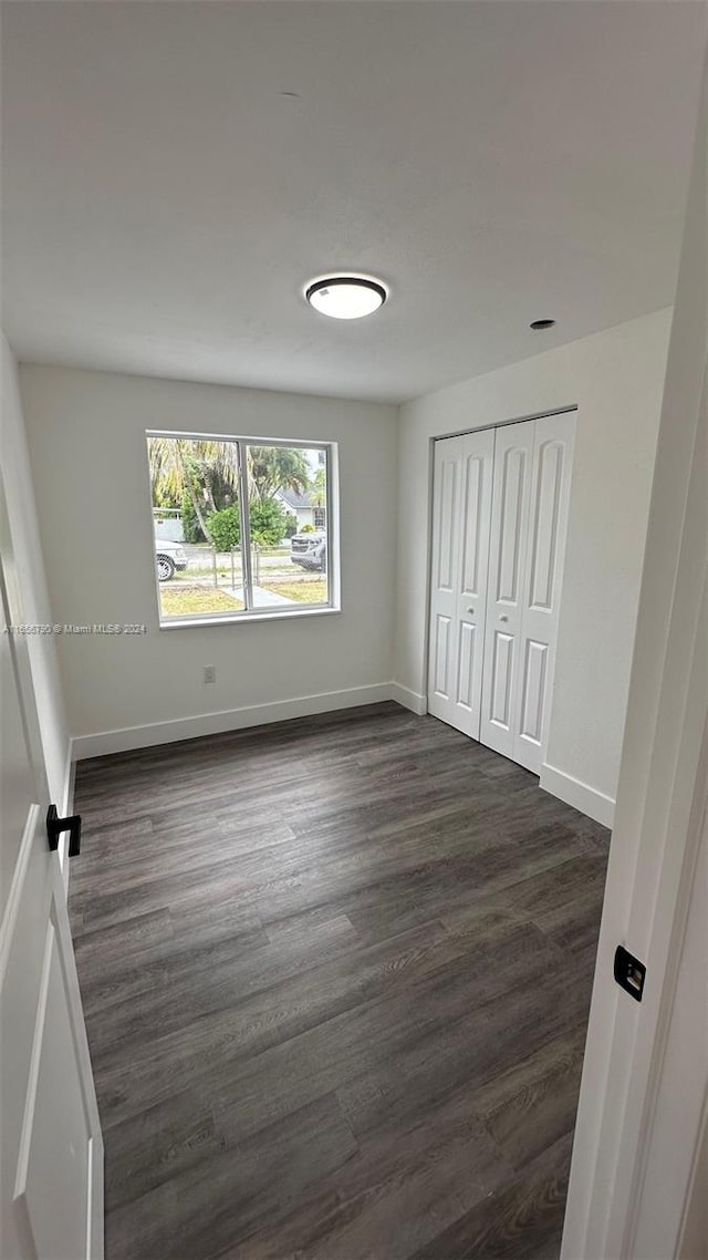 unfurnished bedroom featuring dark wood-type flooring and a closet