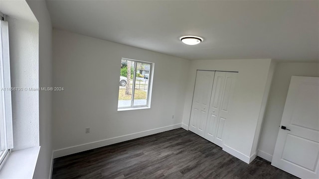 unfurnished bedroom with lofted ceiling, dark hardwood / wood-style floors, and a closet