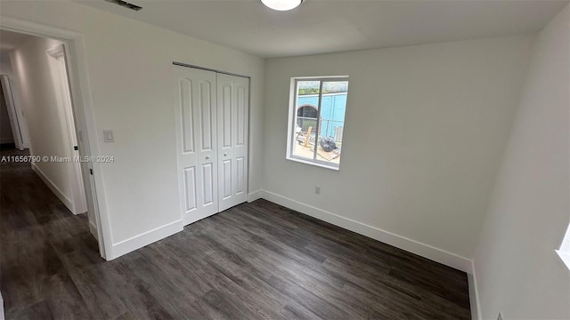 unfurnished bedroom with a closet and dark hardwood / wood-style flooring