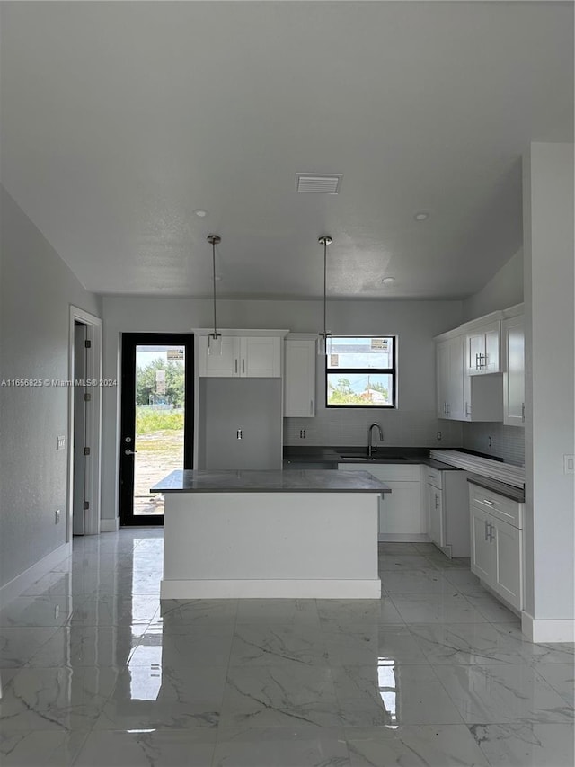 kitchen featuring white cabinets, decorative light fixtures, and a kitchen island