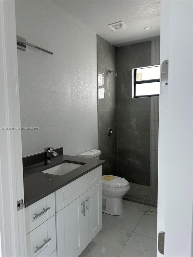 bathroom featuring vanity, toilet, and tiled shower