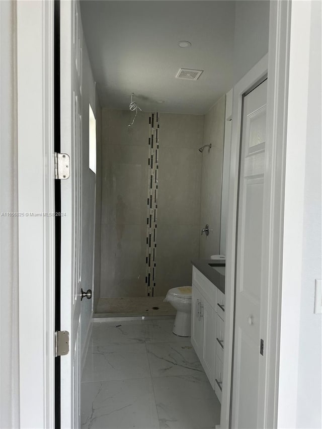 bathroom featuring toilet, vanity, and tiled shower