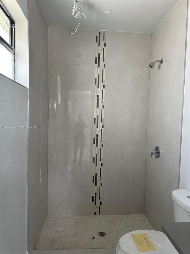 bathroom with tiled shower, vanity, and toilet