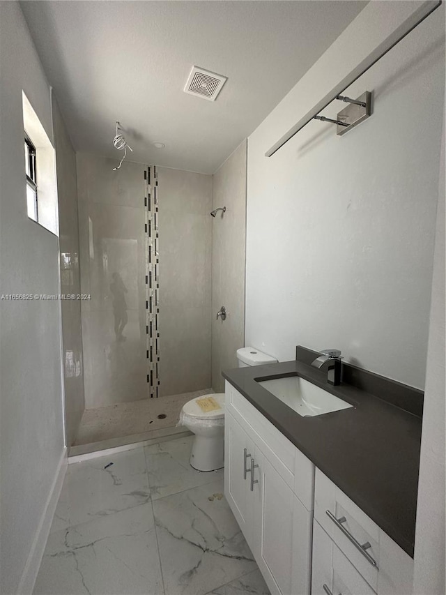 bathroom with toilet, vanity, and tiled shower