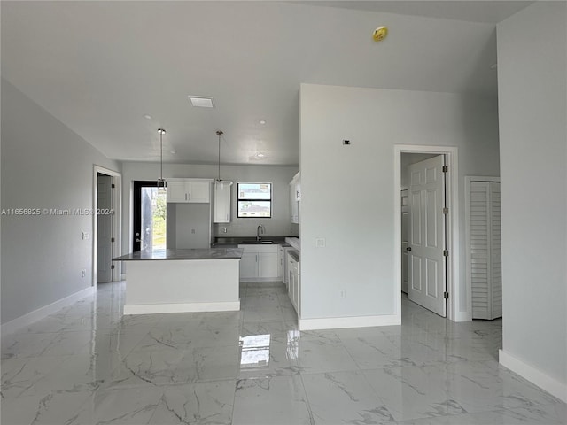 kitchen with a center island, sink, white cabinetry, and hanging light fixtures