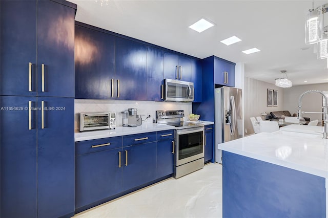 kitchen featuring blue cabinetry, pendant lighting, appliances with stainless steel finishes, and decorative backsplash