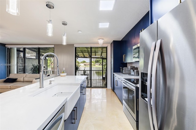 kitchen featuring appliances with stainless steel finishes, blue cabinets, sink, and decorative light fixtures