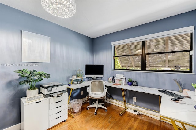 office with light hardwood / wood-style floors and a notable chandelier