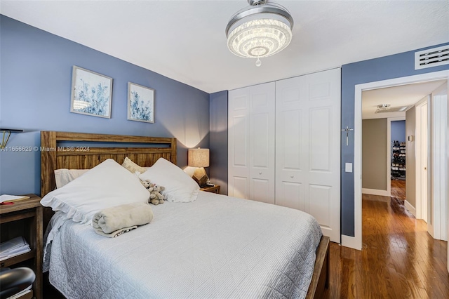 bedroom with dark wood-type flooring, a closet, and a notable chandelier